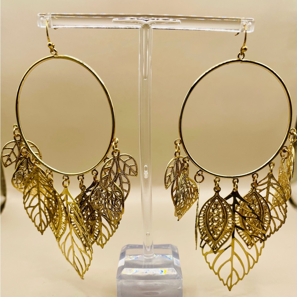 Gold tone hope earrings with metal leaf dangles of various sizes. Statement item